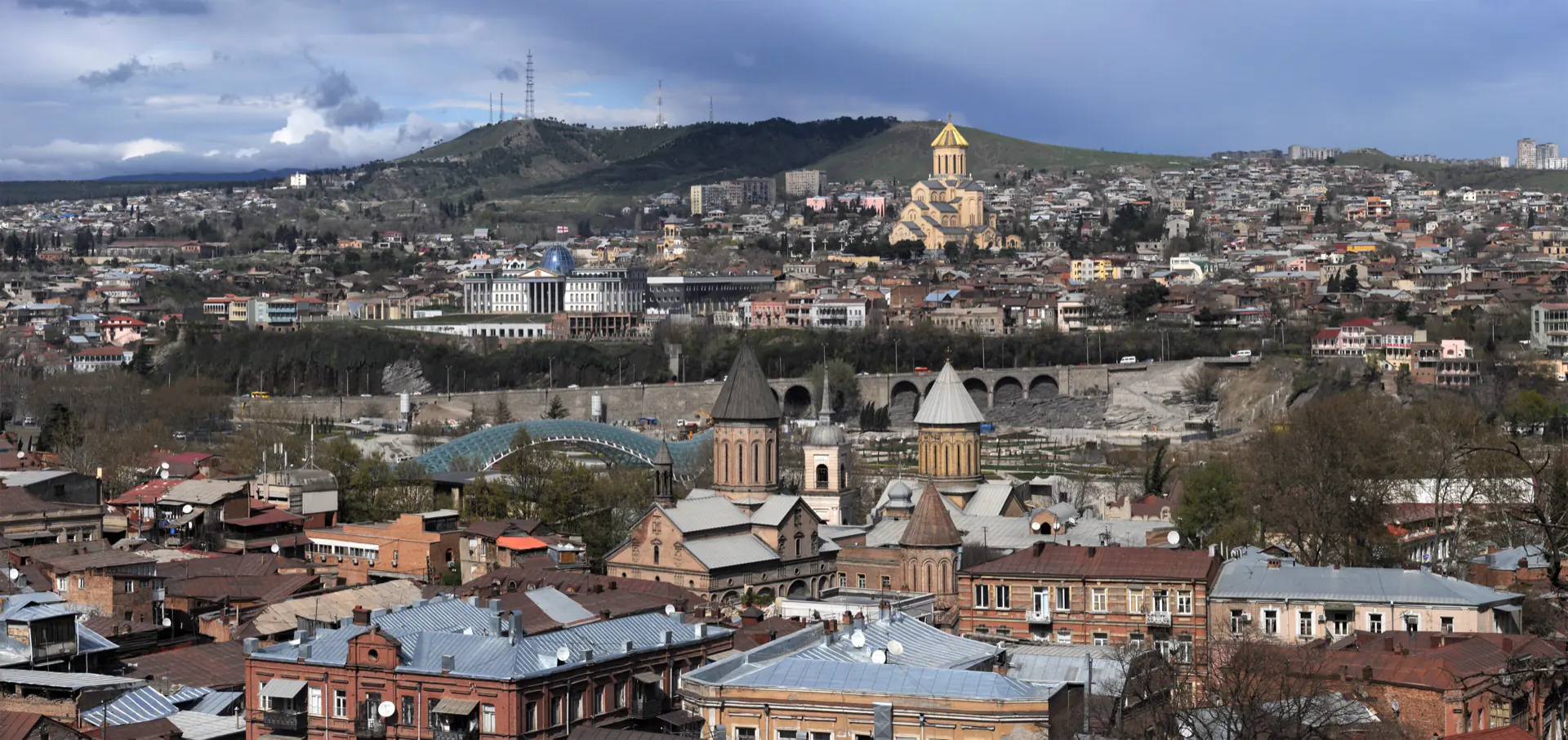 Tbilisi from Narikala: tiled roofs and wooden balconies stepping down to the Mtkvari.