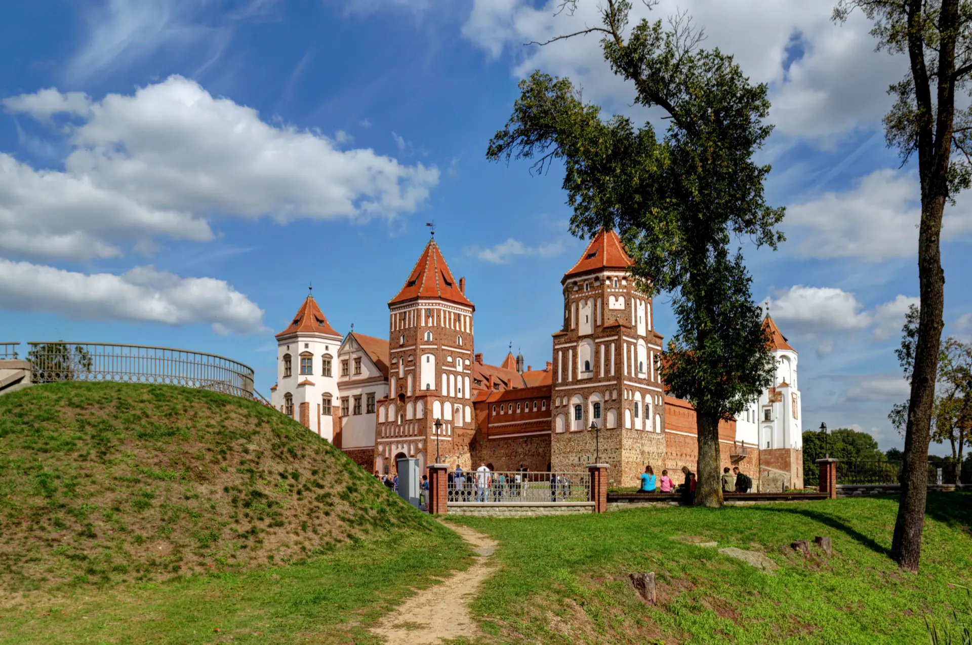 The red-brick towers of Mir Castle above the earthwork and the path to the gate.