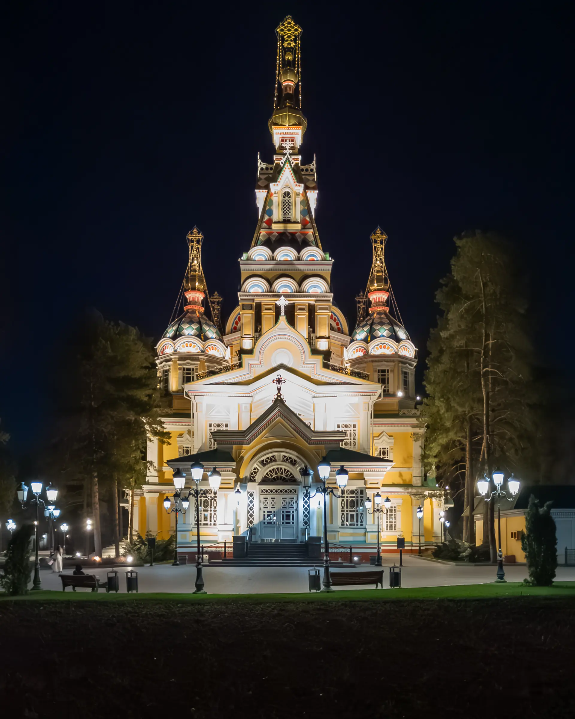 The wooden Ascension Cathedral in Almaty, floodlit after dark.
