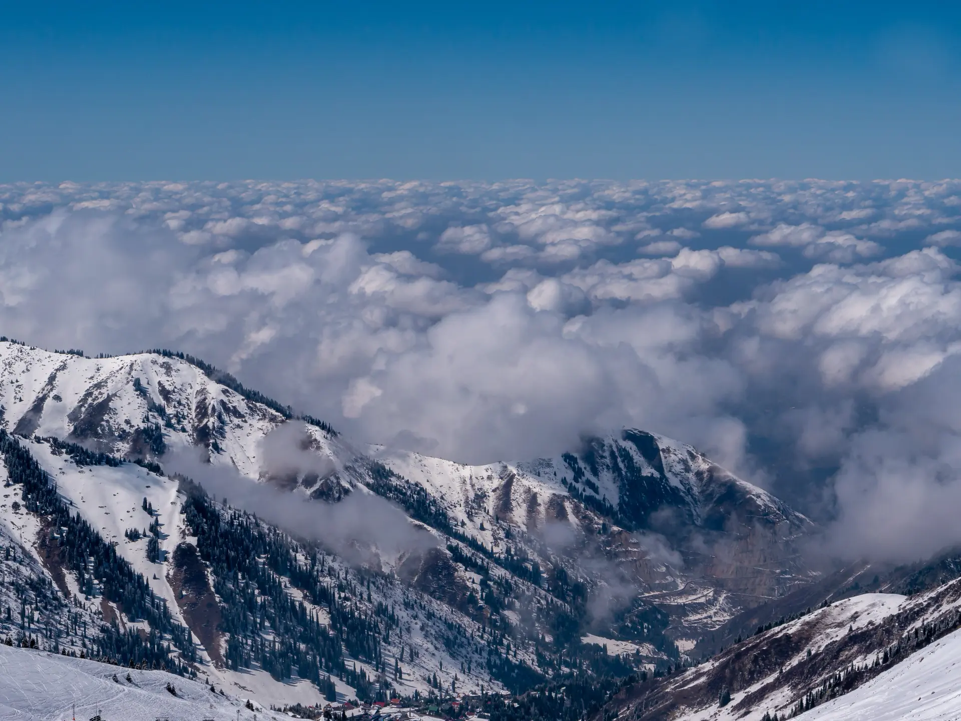 Snow peaks above Shymbulak rising out of a sea of cloud.