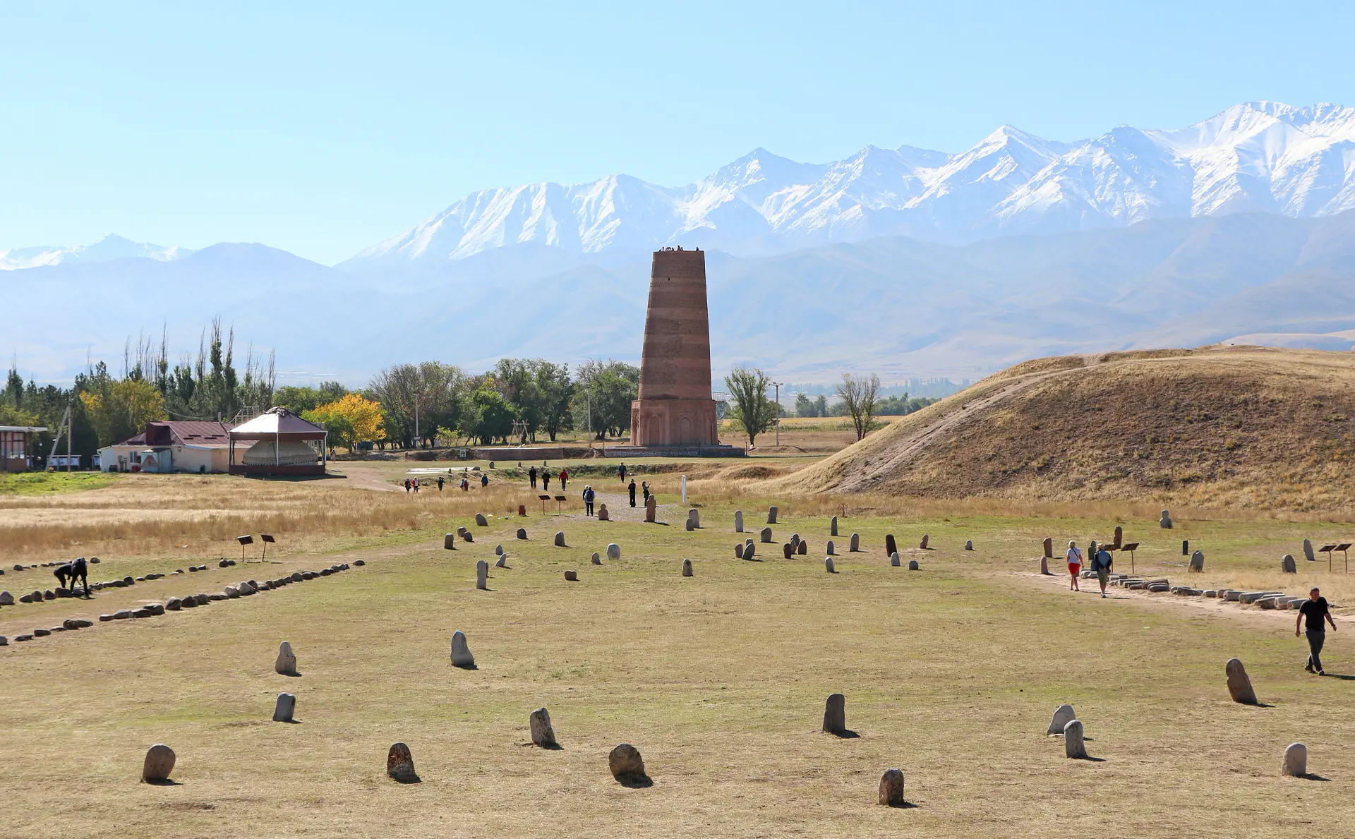 The Burana minaret on the steppe with its field of stone balbals and the mountains behind.