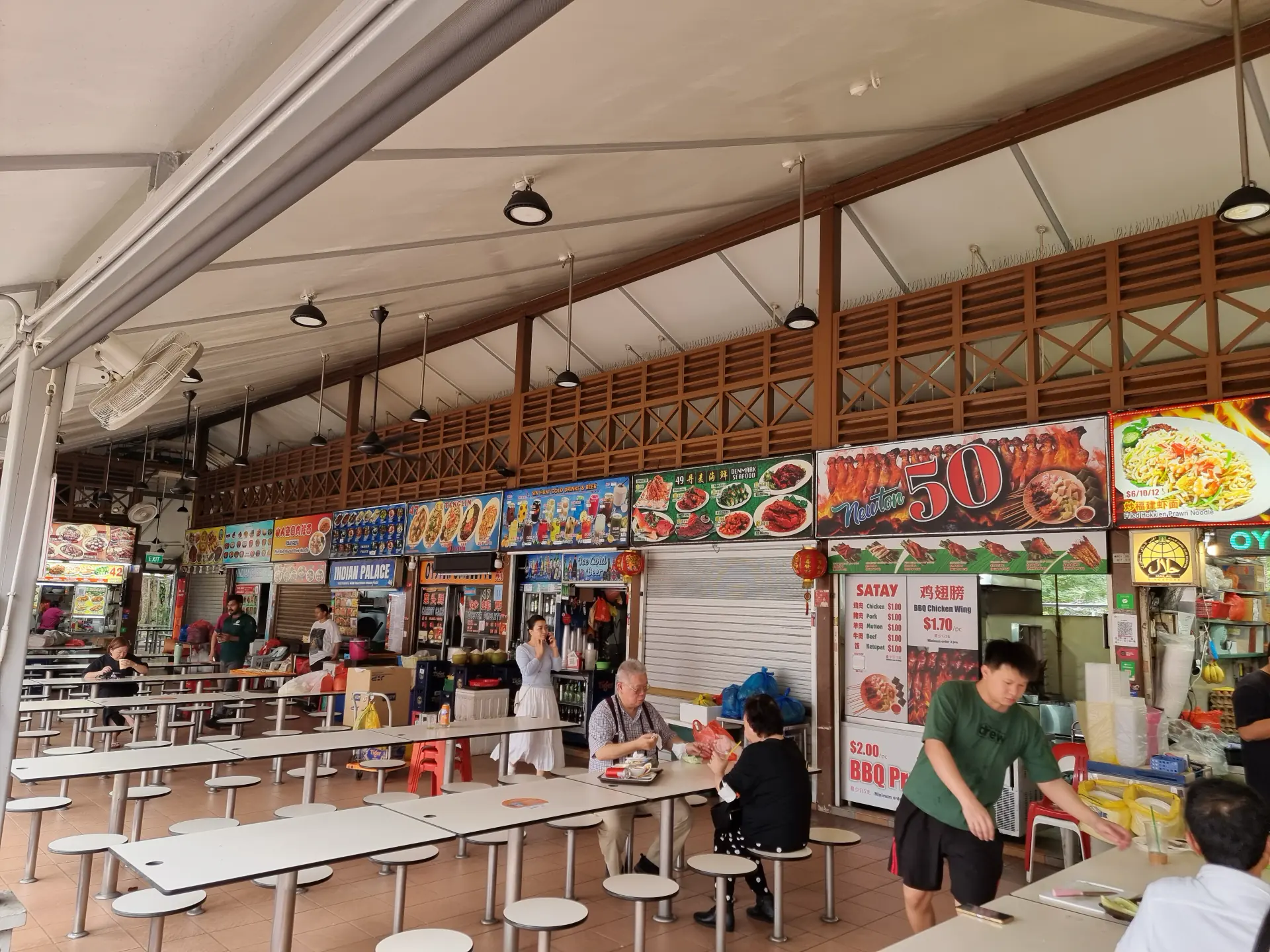 Stalls and communal tables inside a Singapore hawker centre.