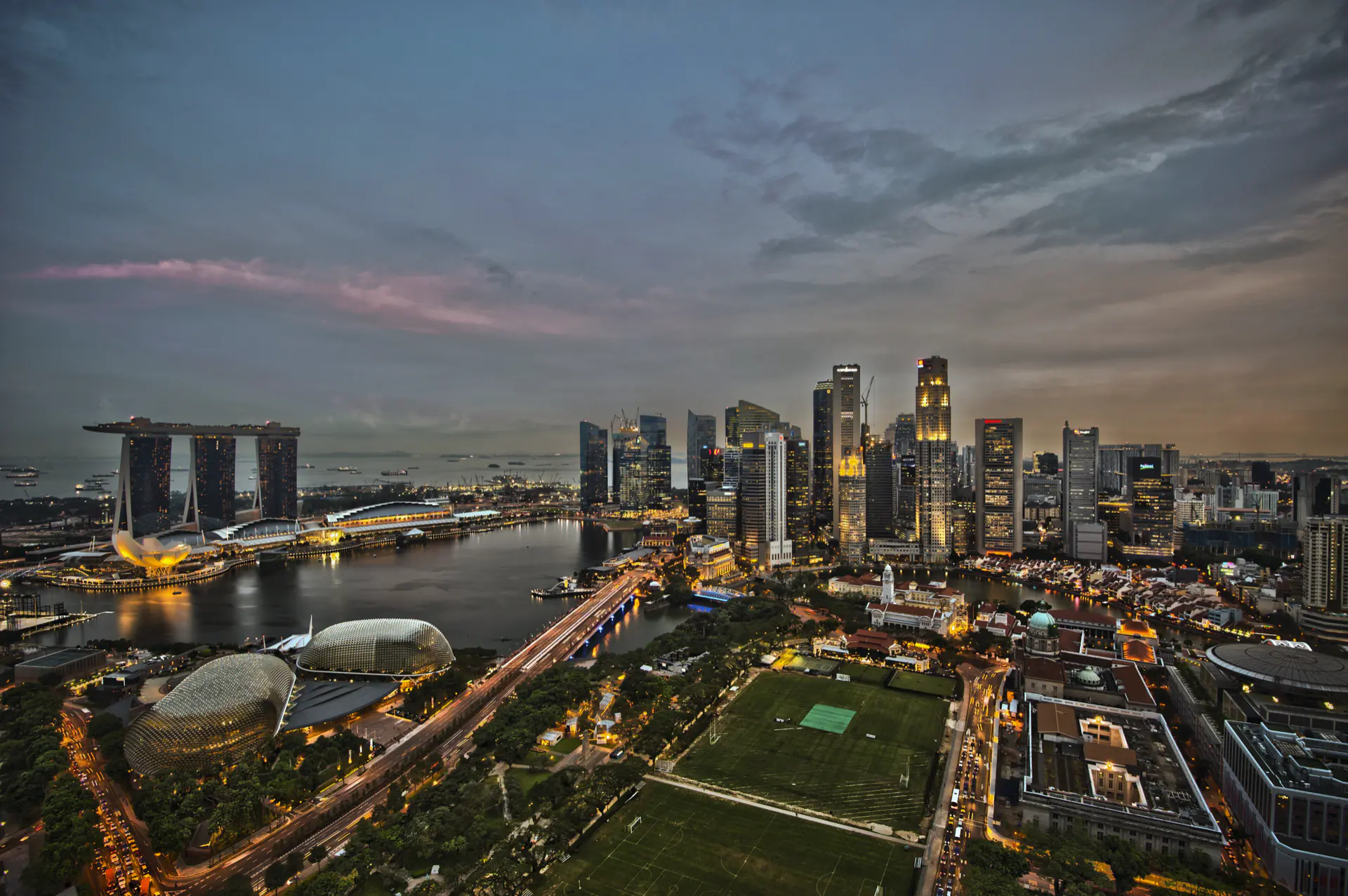 The Singapore skyline at dusk across the water, towers stacked along the bay.