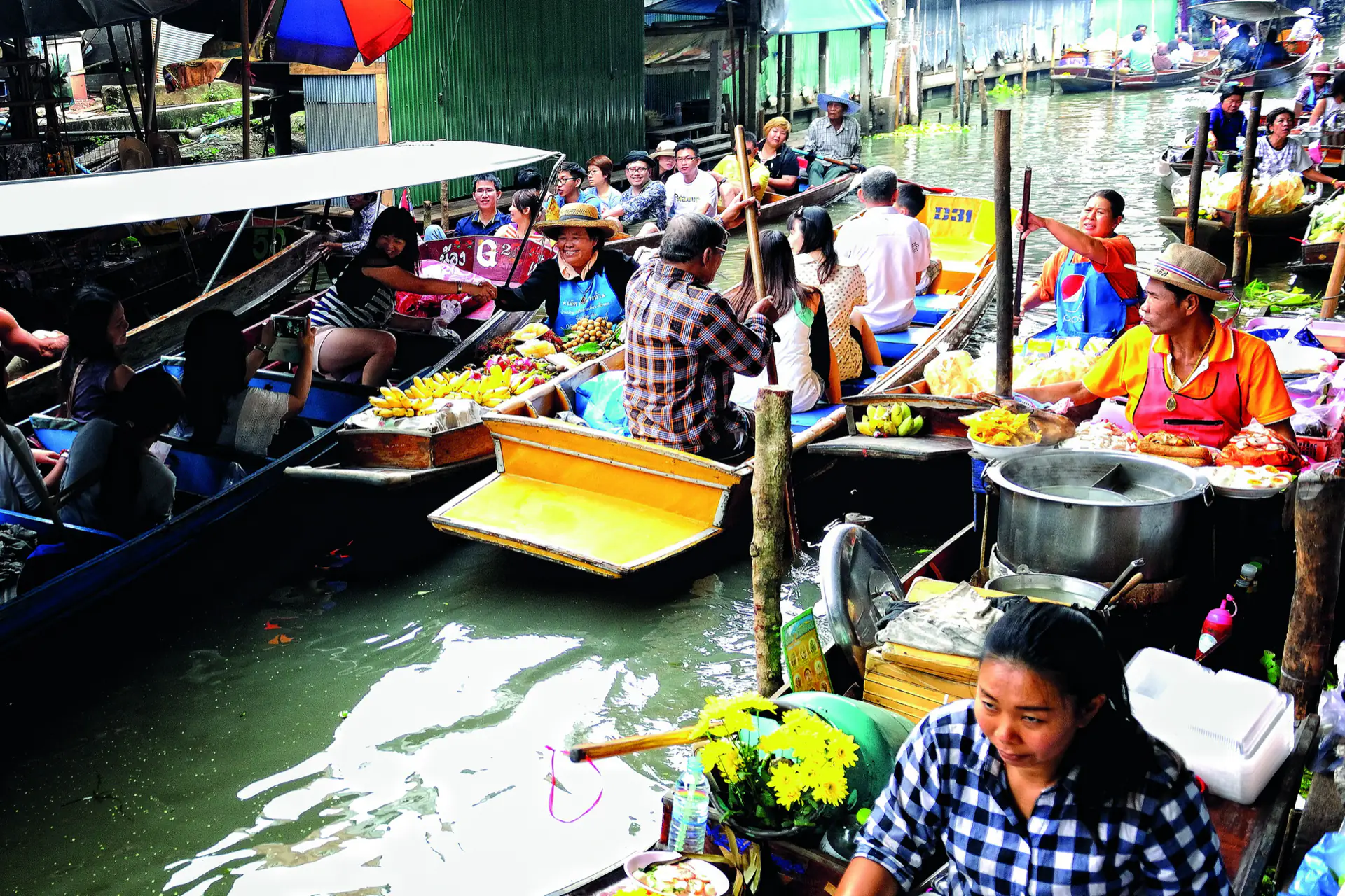 Boats loaded with fruit and flowers packed together at the Damnoen Saduak floating market.