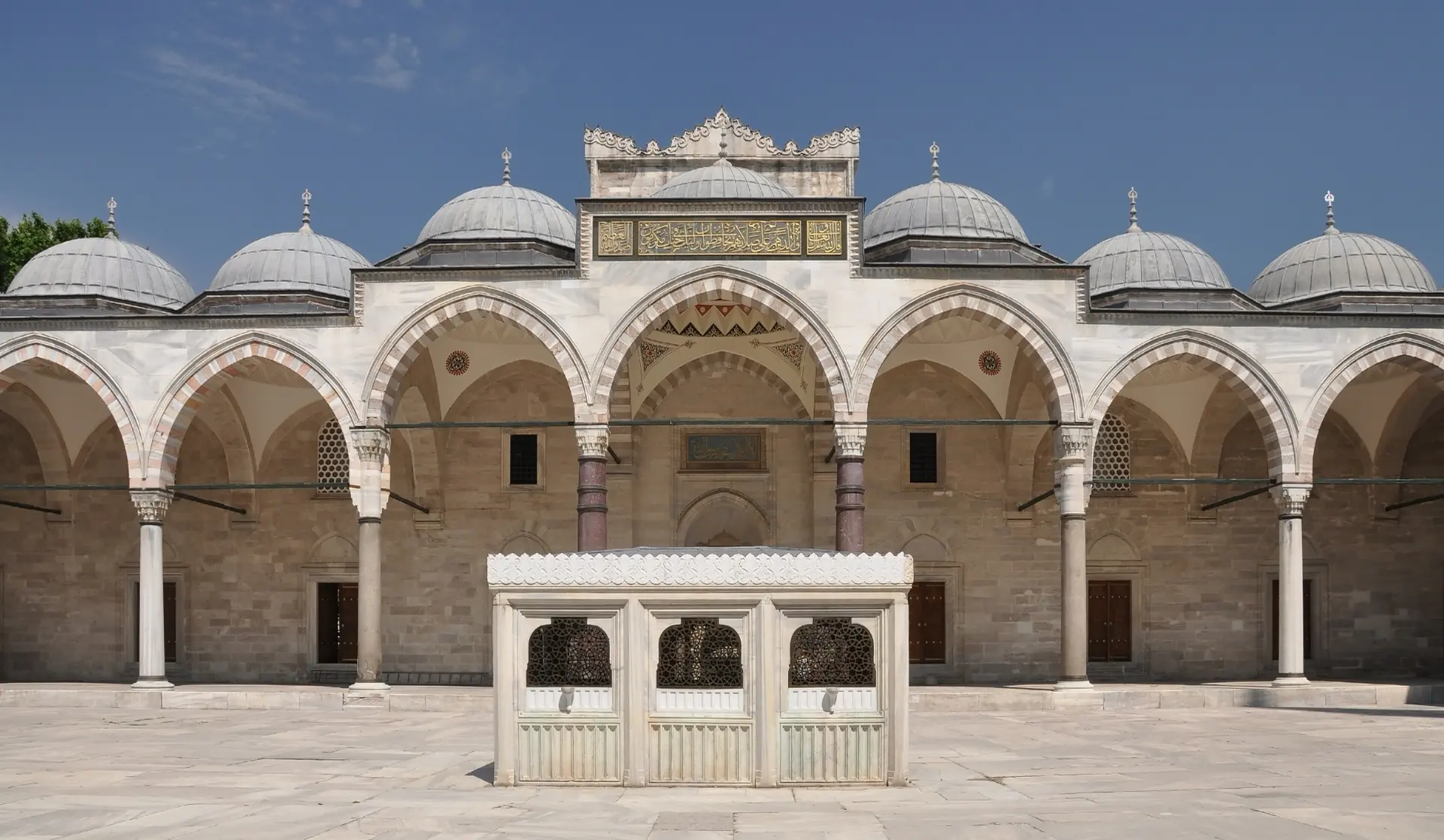 The arcaded courtyard of the Süleymaniye Mosque under a clear sky.