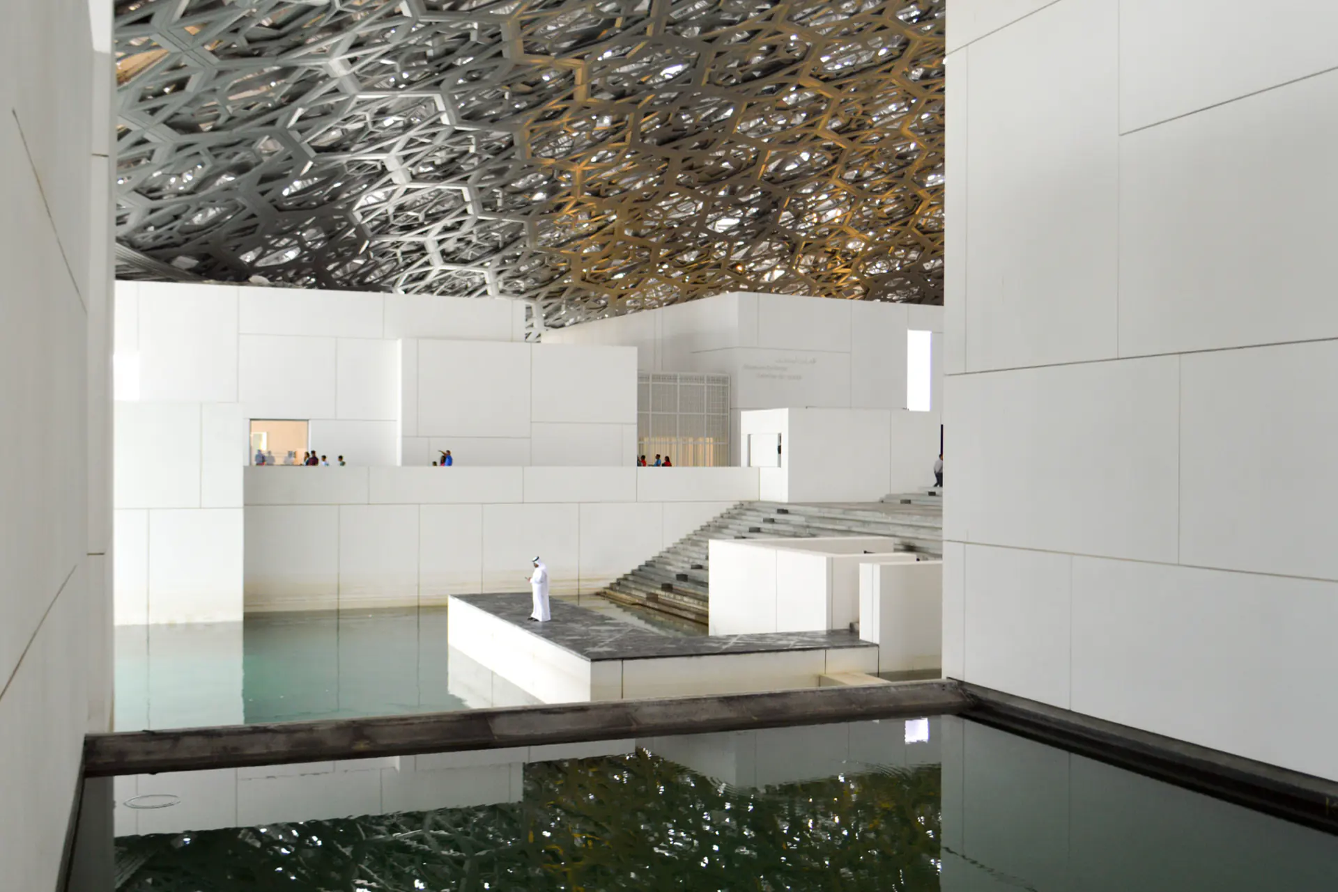 Dappled light falling through the Louvre Abu Dhabi dome onto the water below.