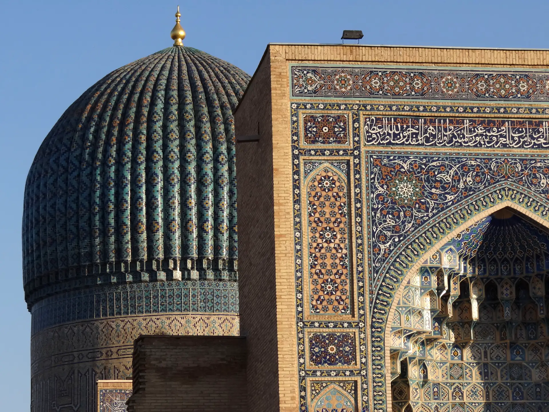 The ribbed turquoise dome of the Gur-e-Amir mausoleum above its tiled facade.